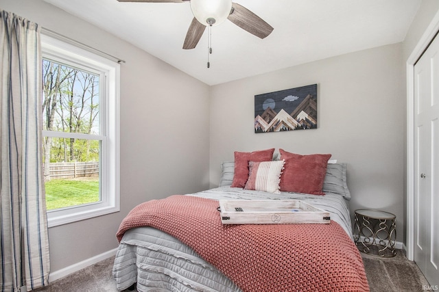 carpeted bedroom featuring baseboards, a ceiling fan, a closet, and multiple windows