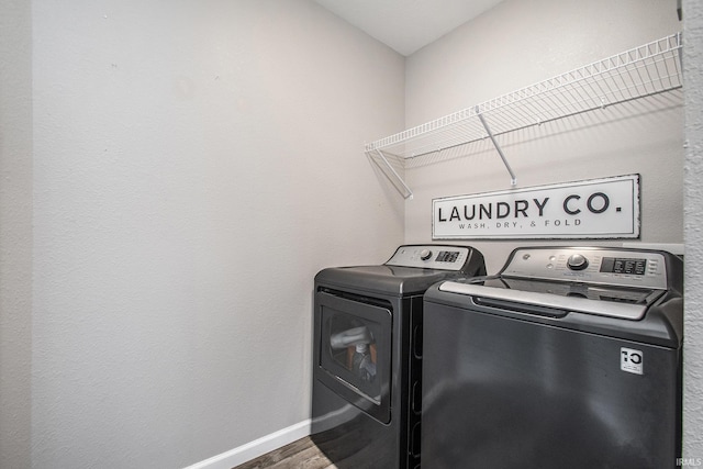 laundry room featuring laundry area, baseboards, independent washer and dryer, and wood finished floors