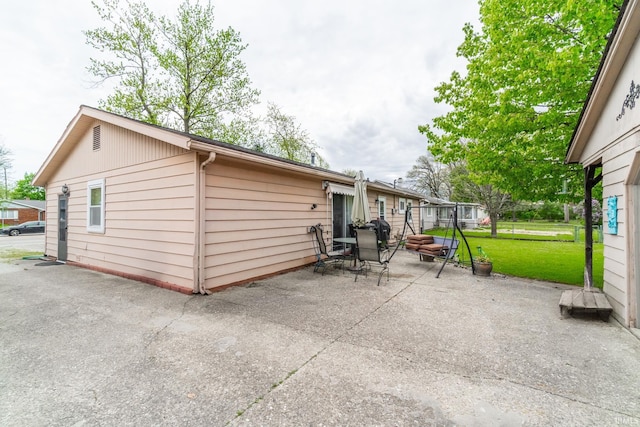 back of house with a lawn and a patio