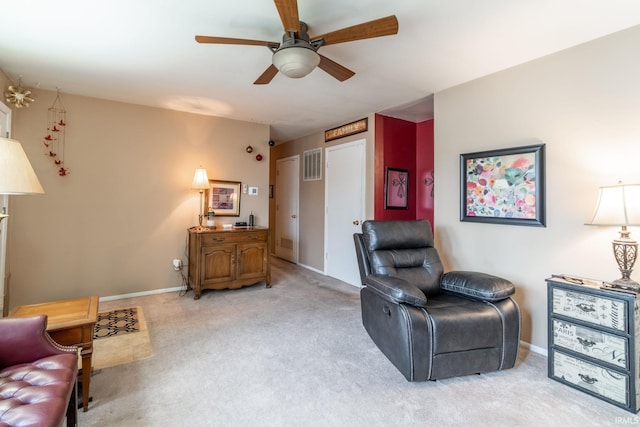 living area with visible vents, baseboards, ceiling fan, and light colored carpet