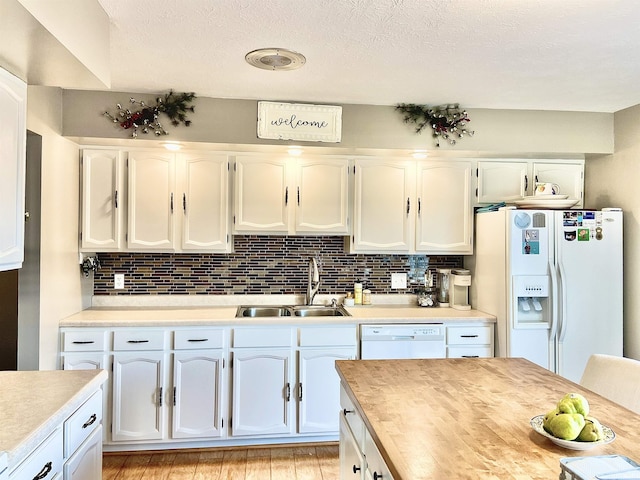 kitchen featuring backsplash, a sink, light countertops, white cabinets, and white appliances