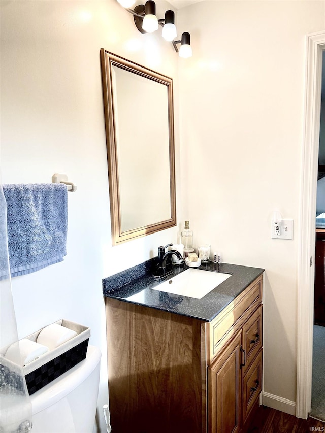 half bathroom featuring vanity, wood finished floors, and toilet