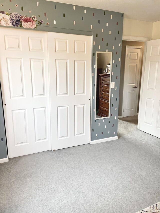 unfurnished bedroom featuring baseboards, carpet, and a closet