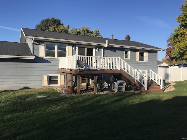 rear view of property with a chimney, a lawn, a wooden deck, fence, and stairs