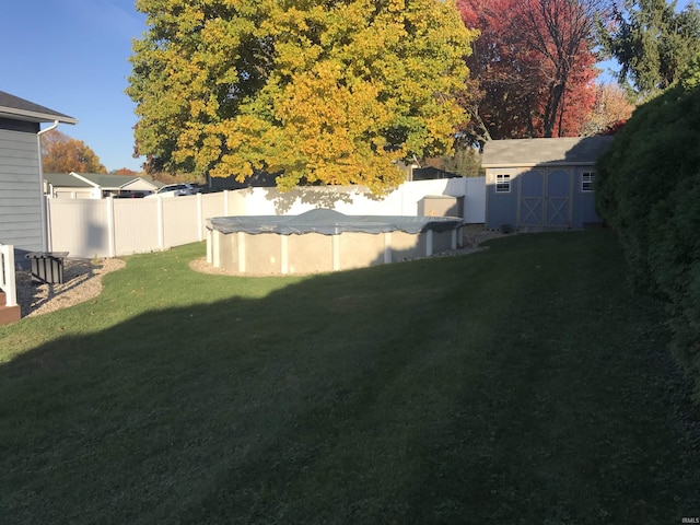 view of yard featuring a fenced backyard, a fenced in pool, an outdoor structure, and a shed