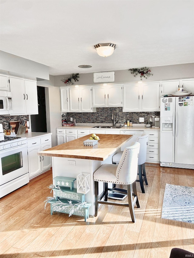 kitchen featuring a sink, white cabinets, and white appliances