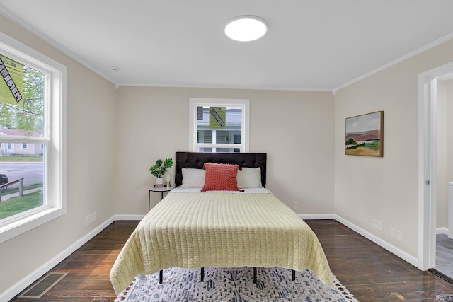 bedroom with visible vents, dark wood finished floors, crown molding, and baseboards