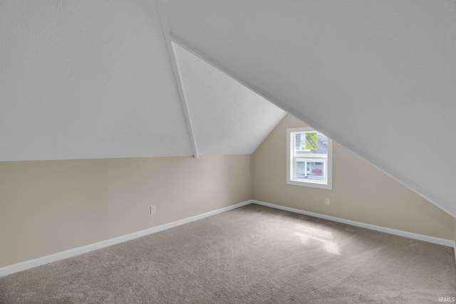 additional living space featuring vaulted ceiling, baseboards, and carpet flooring