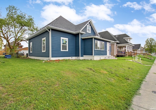 view of front facade with fence, a shingled roof, and a front lawn