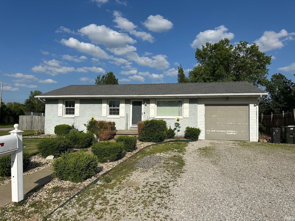 ranch-style house featuring brick siding, an attached garage, fence, and driveway