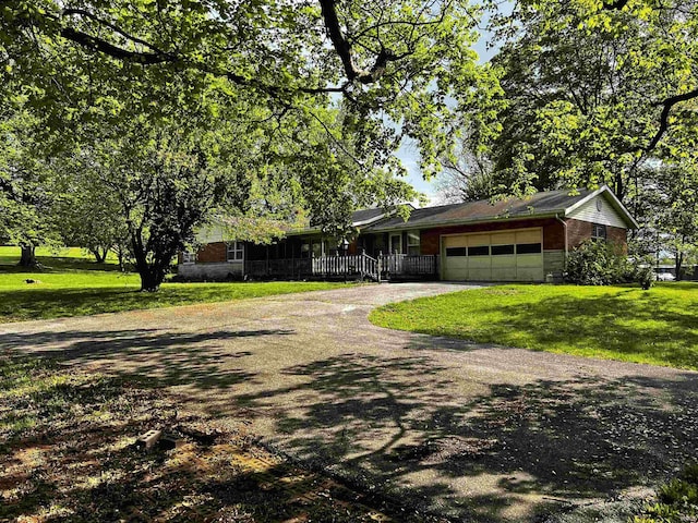 single story home featuring an attached garage, a front yard, driveway, and brick siding