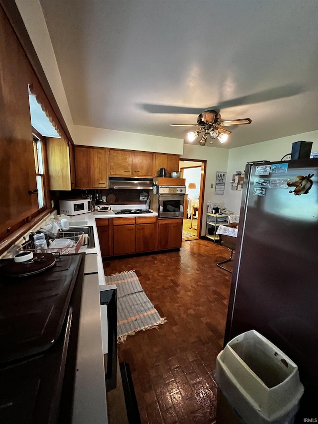 607 Troy Rd, Washington, IN 47501 - kitchen with light countertops, brown cabinetry, stainless steel appliances, a ceiling fan, and under cabinet range hood