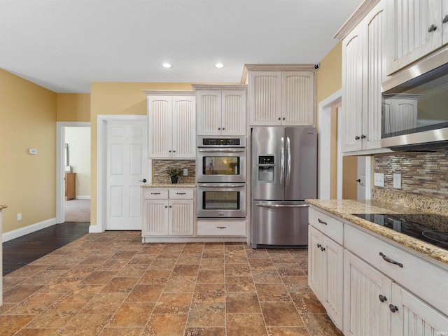 kitchen with appliances with stainless steel finishes, stone finish floor, recessed lighting, baseboards, and backsplash