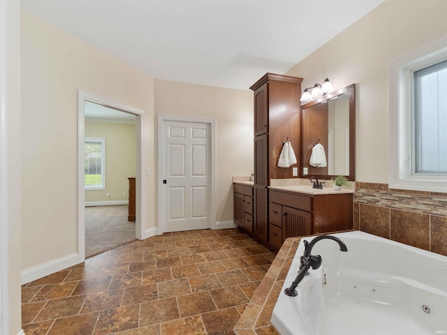 bathroom with vanity, baseboards, stone finish flooring, and a jetted tub