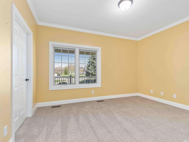 empty room with crown molding, baseboards, carpet flooring, and visible vents
