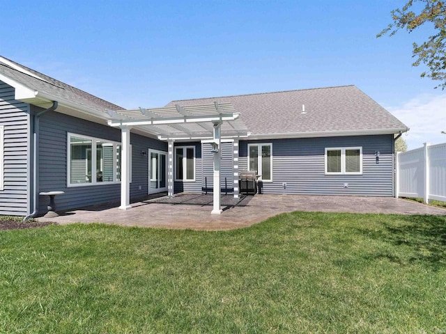 rear view of property featuring roof with shingles, a pergola, a yard, and a patio area