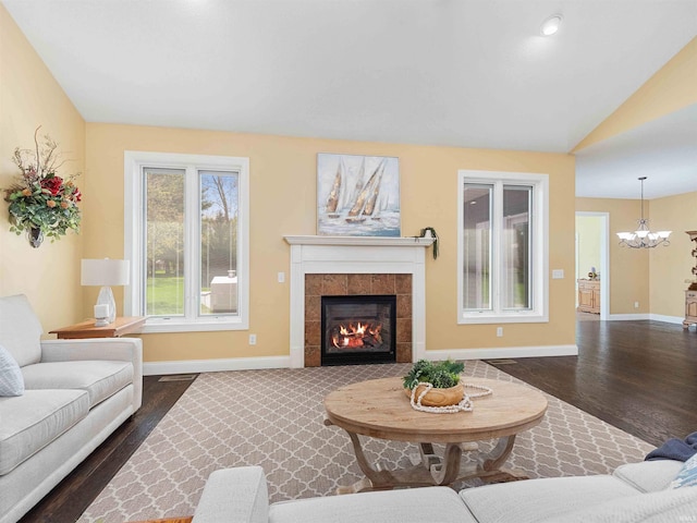 living area with a fireplace, baseboards, a chandelier, and dark wood-type flooring