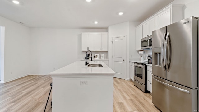 kitchen featuring appliances with stainless steel finishes, a sink, white cabinets, light wood-style floors, and recessed lighting