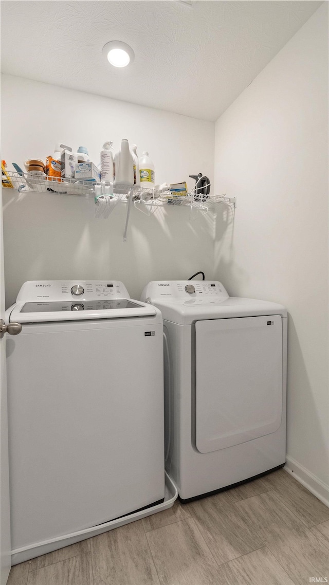 laundry room featuring separate washer and dryer, laundry area, light wood finished floors, and baseboards