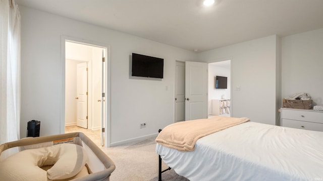 bedroom featuring light colored carpet, baseboards, and ensuite bathroom