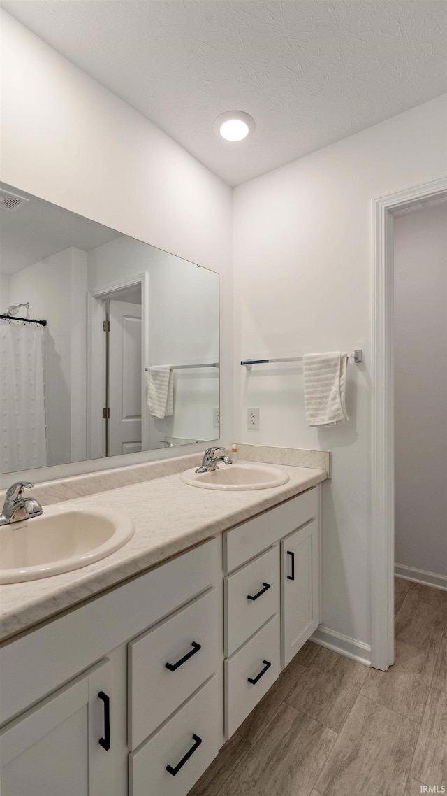 full bath with a sink, baseboards, double vanity, and visible vents