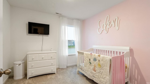 bedroom with a crib, visible vents, baseboards, and light colored carpet