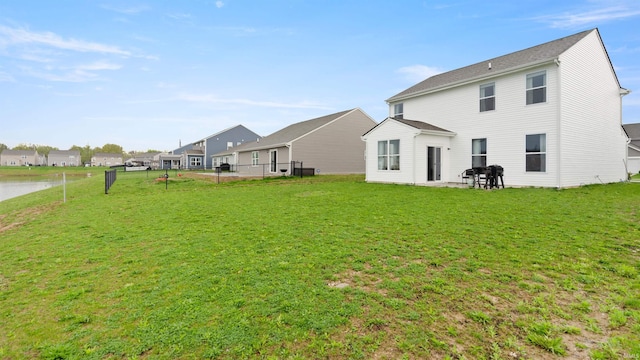 rear view of house featuring fence and a yard