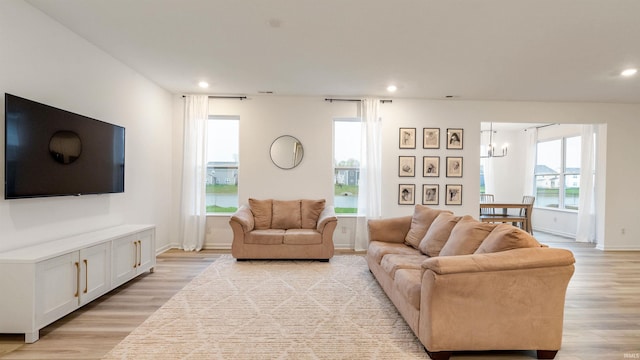 living area with an inviting chandelier, recessed lighting, light wood finished floors, and baseboards