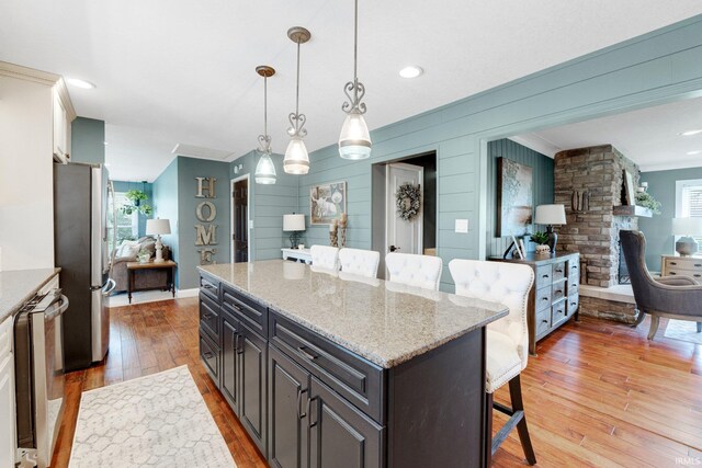 119 Southridge Dr, Fort Wayne, IN 46825 - kitchen with light stone countertops, appliances with stainless steel finishes, a breakfast bar, light wood-style floors, and a center island