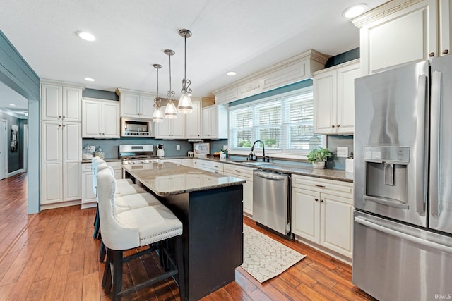 119 Southridge Dr, Fort Wayne, IN 46825 - kitchen with light stone counters, a sink, a center island, stainless steel appliances, and wood finished floors