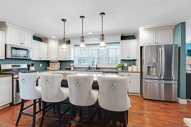 119 Southridge Dr, Fort Wayne, IN 46825 - kitchen with a kitchen island, a breakfast bar area, a sink, dark wood finished floors, and appliances with stainless steel finishes