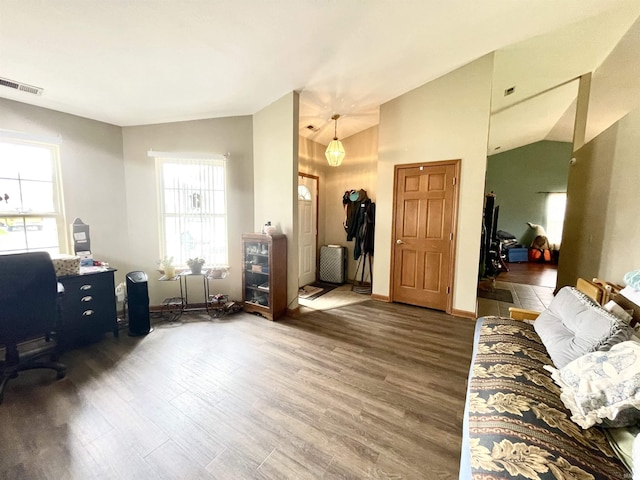 interior space with a wealth of natural light, vaulted ceiling, wood finished floors, and visible vents
