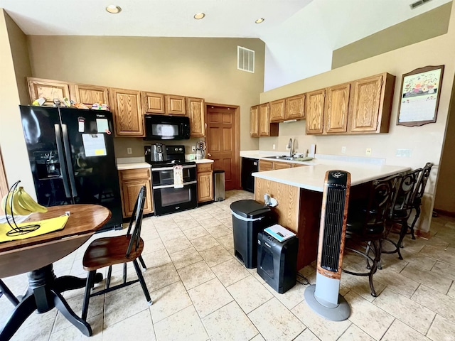 kitchen featuring visible vents, light countertops, high vaulted ceiling, black appliances, and a peninsula