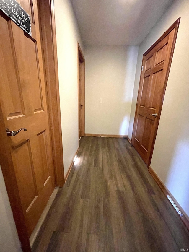 hallway featuring baseboards and dark wood finished floors