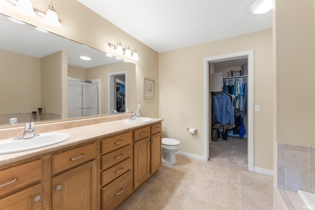 bathroom featuring double vanity, a sink, toilet, and a shower stall