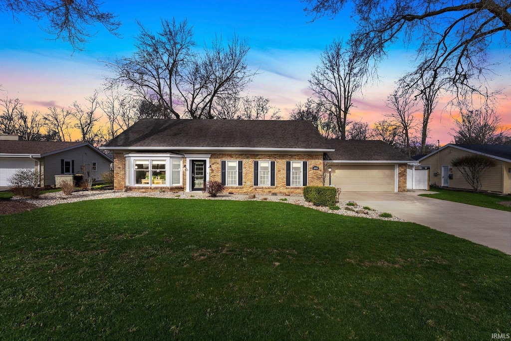 2821 Devon Dr, Fort Wayne, IN 46815 - view of front facade with an attached garage, driveway, a front lawn, and brick siding