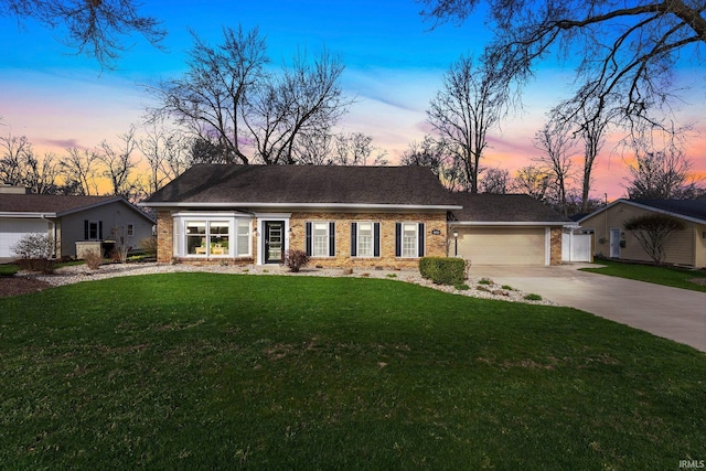 view of front facade with an attached garage, driveway, a front lawn, and brick siding