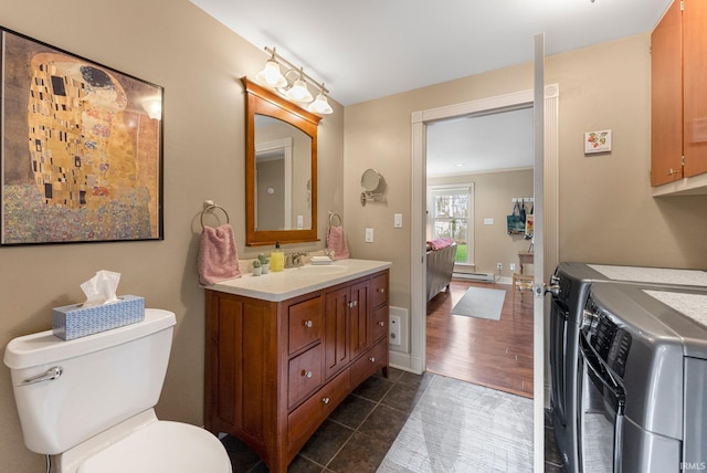 bathroom featuring vanity, toilet, tile patterned floors, a baseboard heating unit, and washing machine and dryer