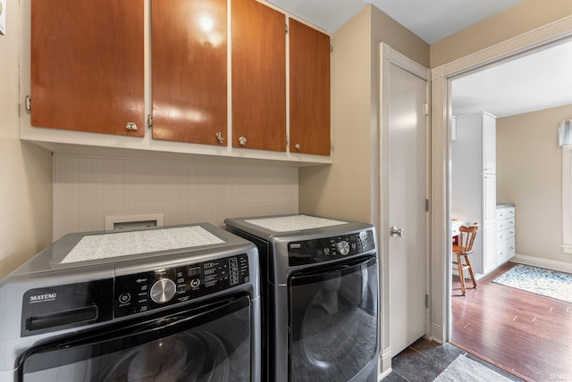 washroom with separate washer and dryer, cabinet space, dark wood-type flooring, and baseboards