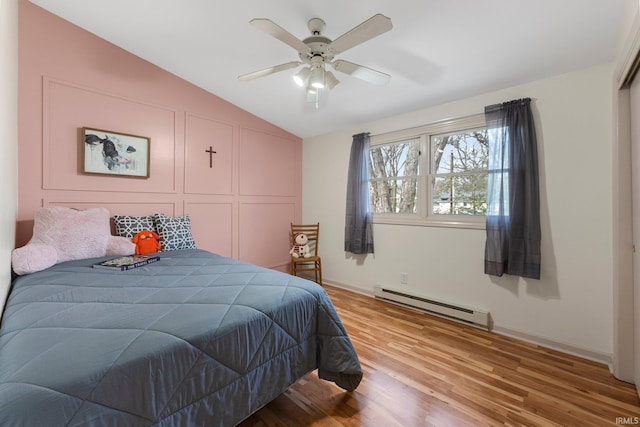 bedroom featuring a closet, lofted ceiling, baseboards, a baseboard heating unit, and light wood finished floors