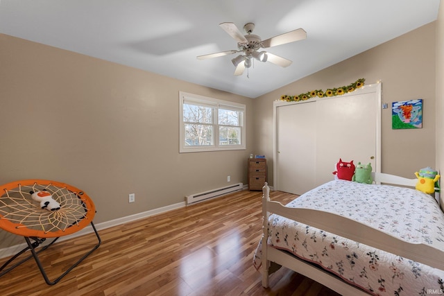 bedroom with vaulted ceiling, light wood-type flooring, baseboards, a baseboard radiator, and a closet