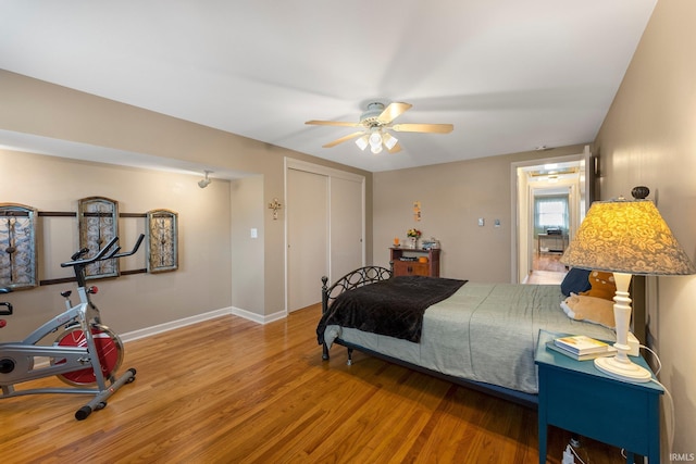 bedroom with baseboards, ceiling fan, a closet, and wood finished floors