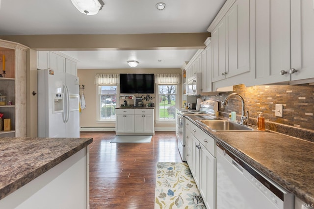 kitchen featuring decorative backsplash, baseboard heating, wood finished floors, a sink, and white appliances