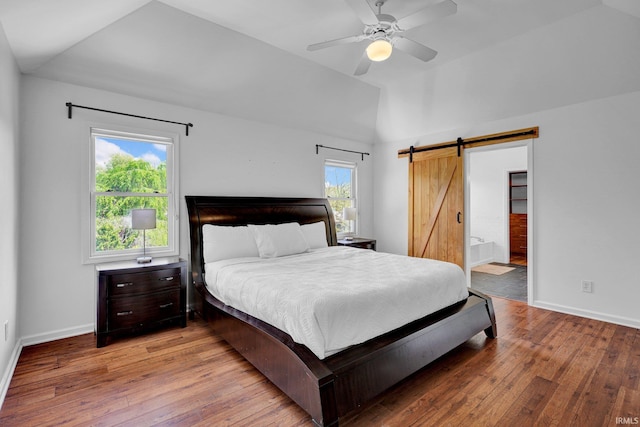 bedroom with baseboards, a barn door, vaulted ceiling, and hardwood / wood-style floors