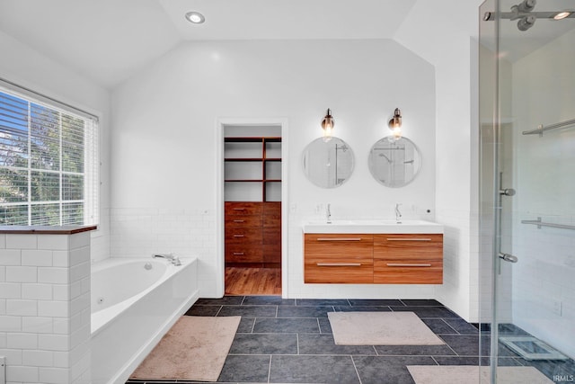 bathroom featuring double vanity, a bath, a stall shower, a sink, and lofted ceiling