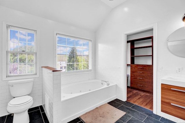 full bath featuring tile patterned flooring, vanity, toilet, a tub with jets, and lofted ceiling
