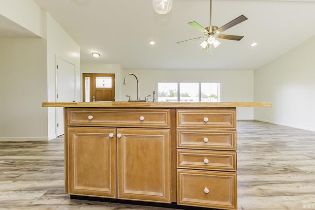 kitchen featuring a ceiling fan, a center island with sink, baseboards, light wood finished floors, and recessed lighting