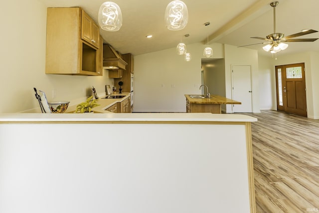 kitchen featuring lofted ceiling with beams, a sink, light countertops, light wood-style flooring, and custom range hood