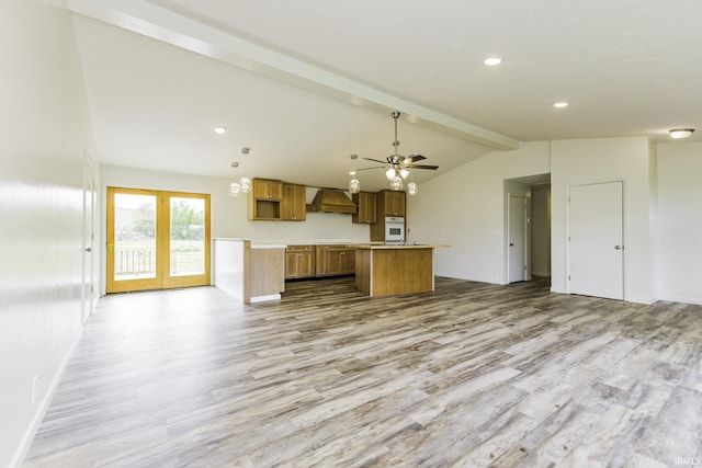 kitchen with a kitchen island, oven, open floor plan, lofted ceiling with beams, and light wood finished floors