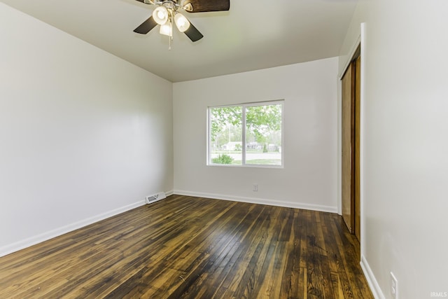 spare room with baseboards, dark wood finished floors, ceiling fan, and visible vents